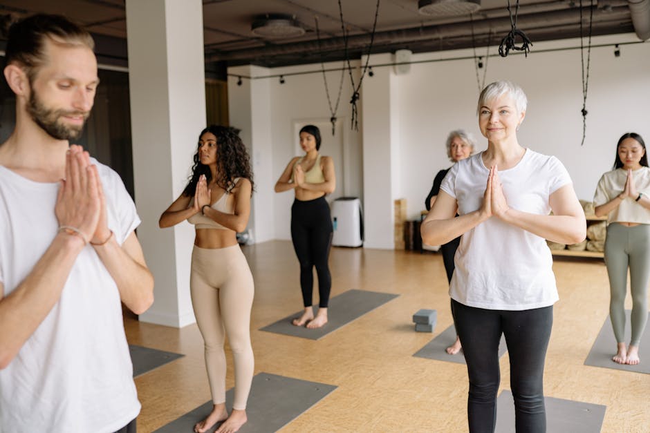 A diverse group of men and women smiling and relaxing during an indoor yoga class